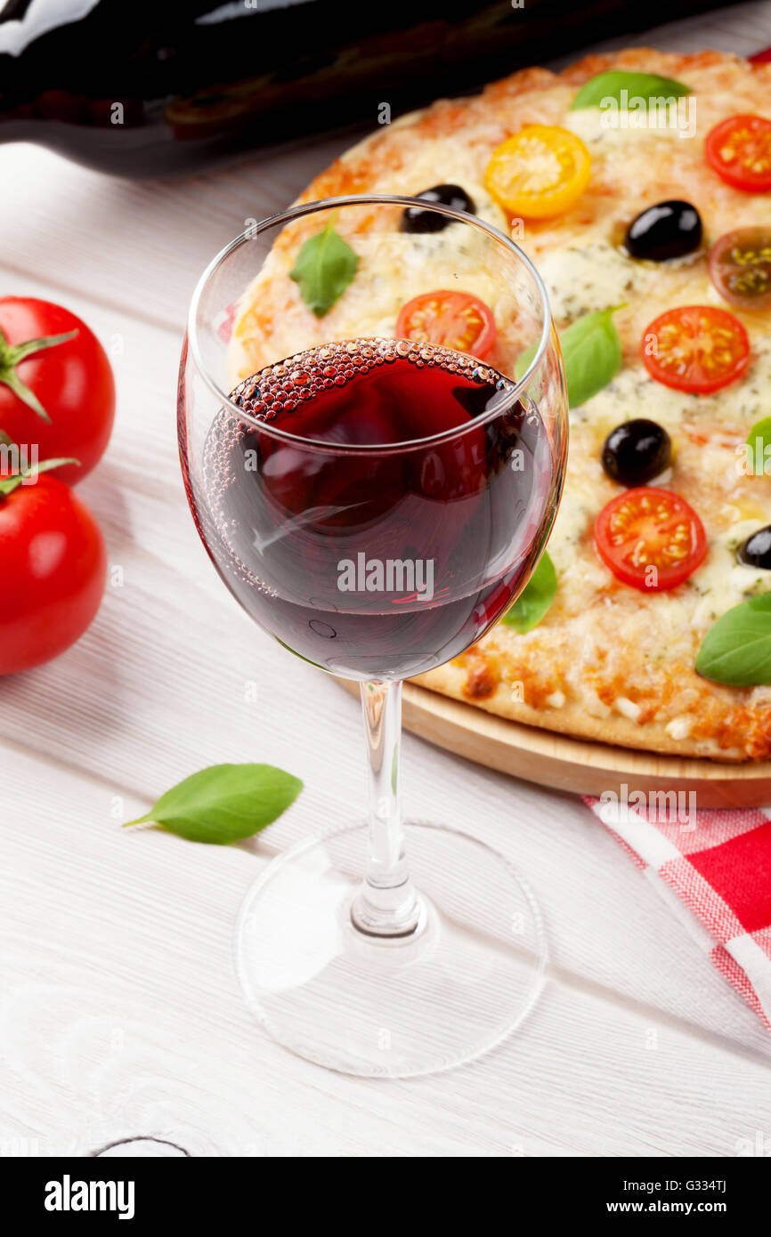 Verre de vin rouge et la pizza italienne avec fromage, tomates, olives et basilic Banque D'Images