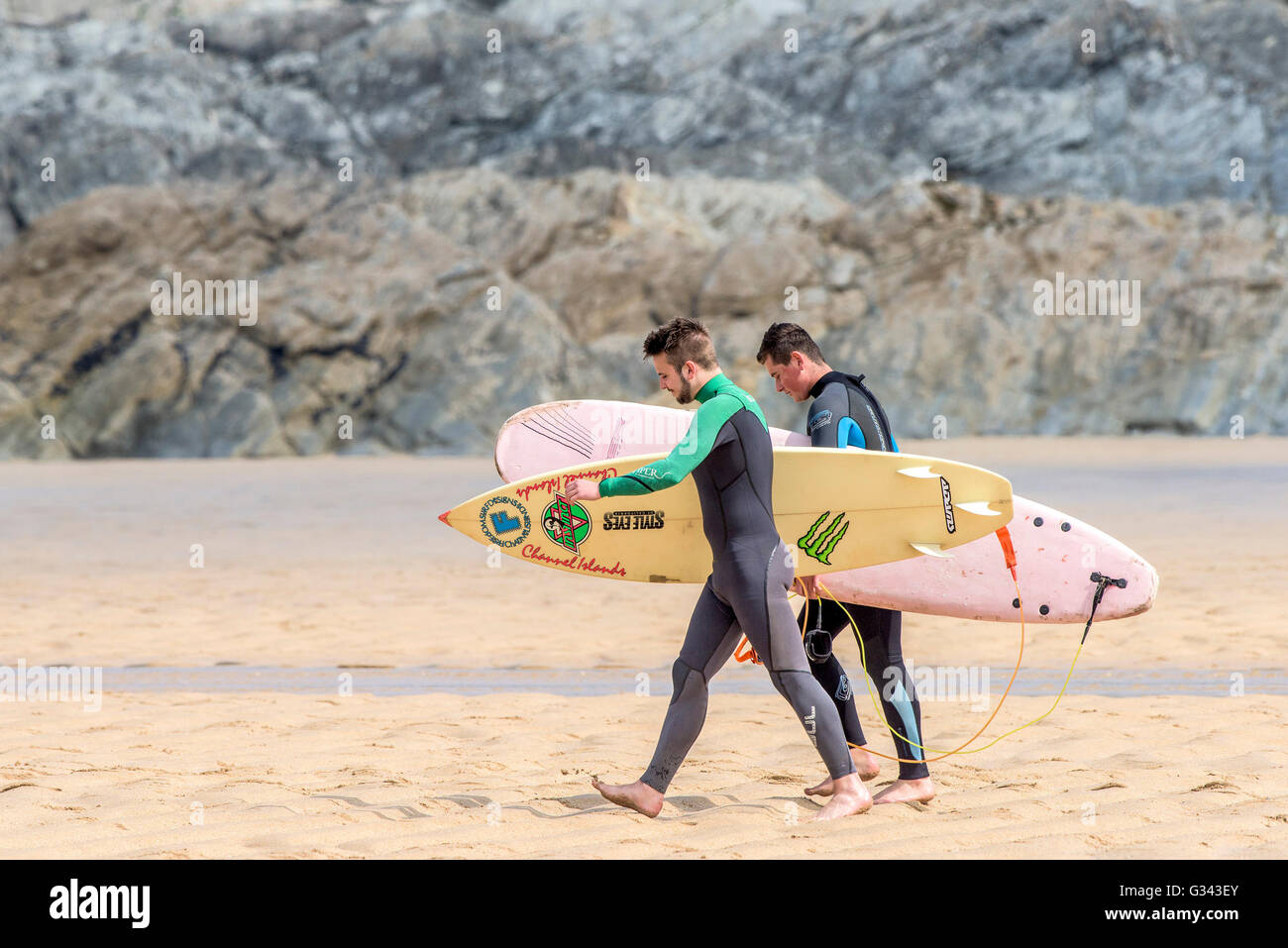 Deux surfeurs de marcher jusqu'à la mer à dans Fistral Newquay, Cornwall. Banque D'Images