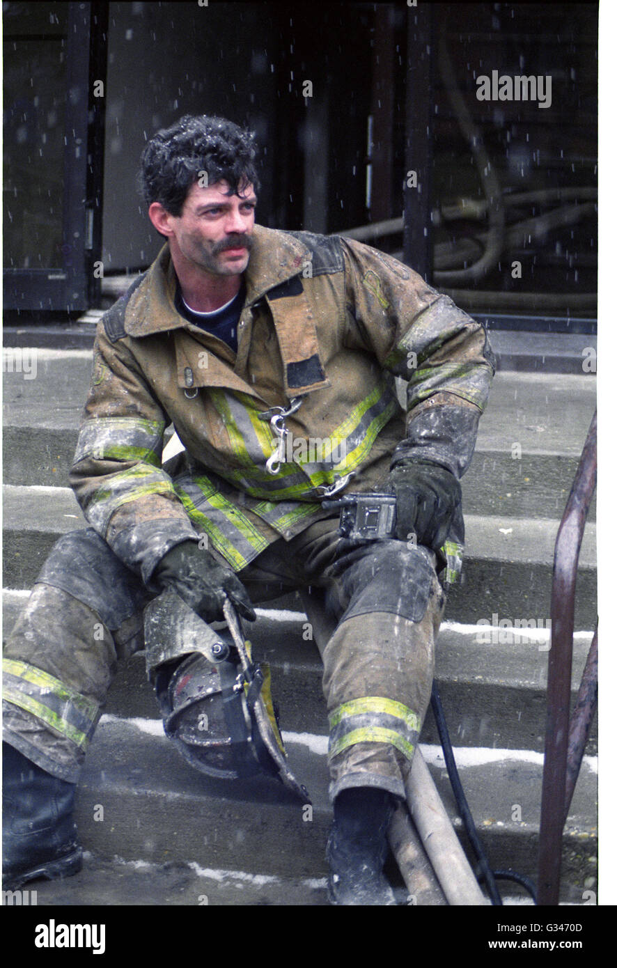 Le pompier prend une pause à partir de la lutte contre l'incendie et qu'il repose sur les étapes alors qu'il neige Banque D'Images
