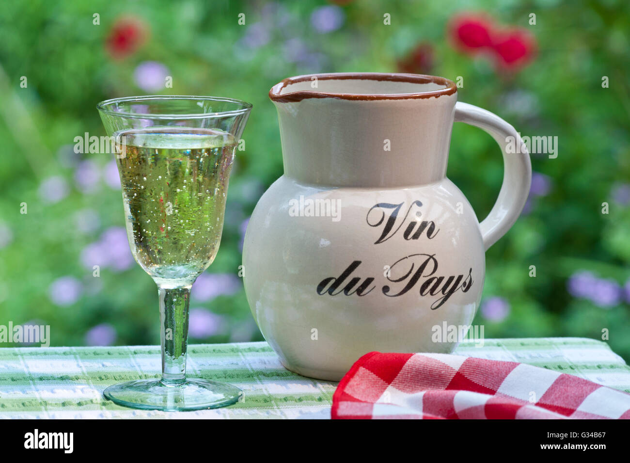 Pichet de vin du pays et de verre réfrigéré simple français pays vin blanc  sur la terrasse ensoleillée en plein air avec table jardin floral derrière  Photo Stock - Alamy