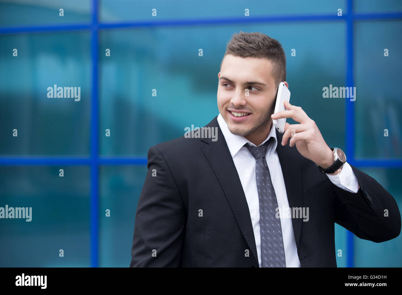 Portrait of young man looking sideways tout en parlant sur smartphone à l'extérieur. Happy handsome man à l'aide de mobile Banque D'Images