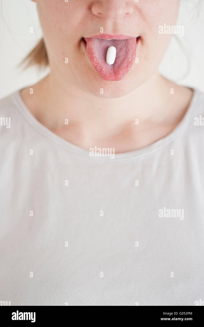 Femme avec un comprimé blanc sur sa langue Banque D'Images