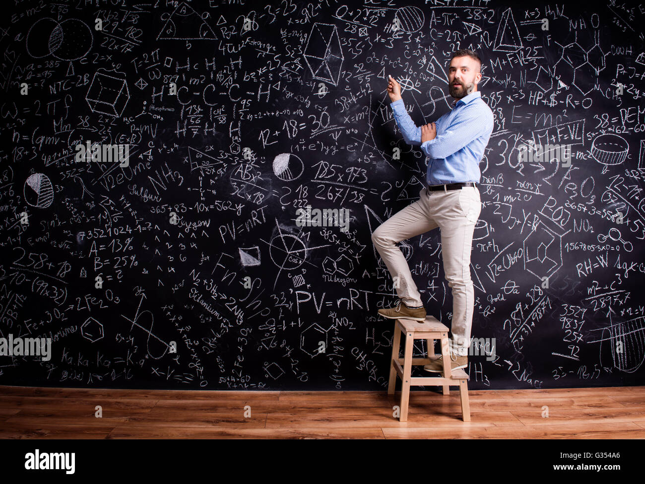 L'homme écrit sur le grand tableau noir avec des symboles mathématiques Banque D'Images