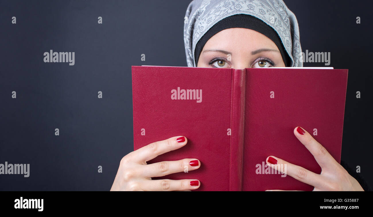 Jeune femme musulmane tenant un livre Banque D'Images