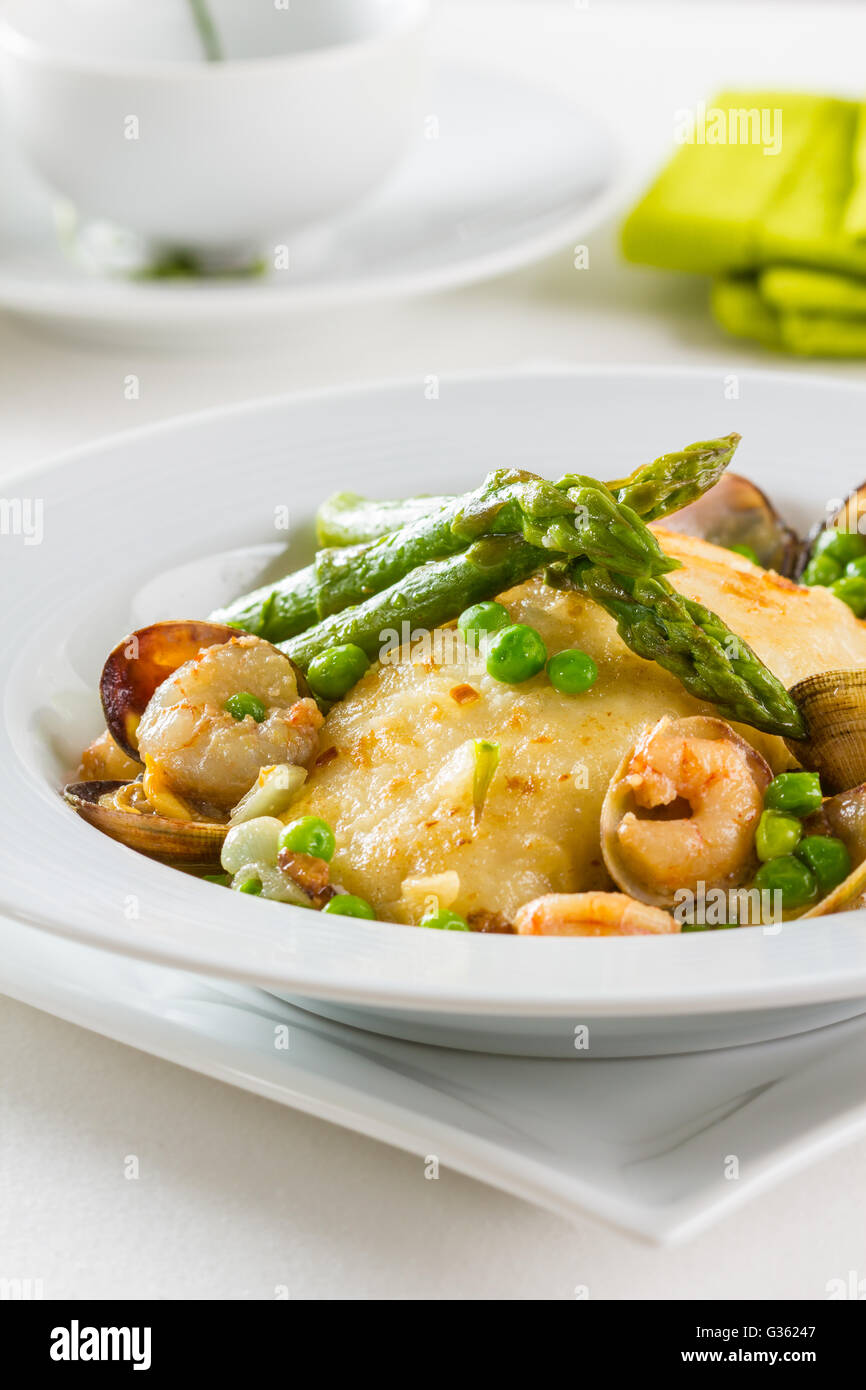 Le merlu aux asperges vertes, petits pois, les crevettes et les palourdes Banque D'Images