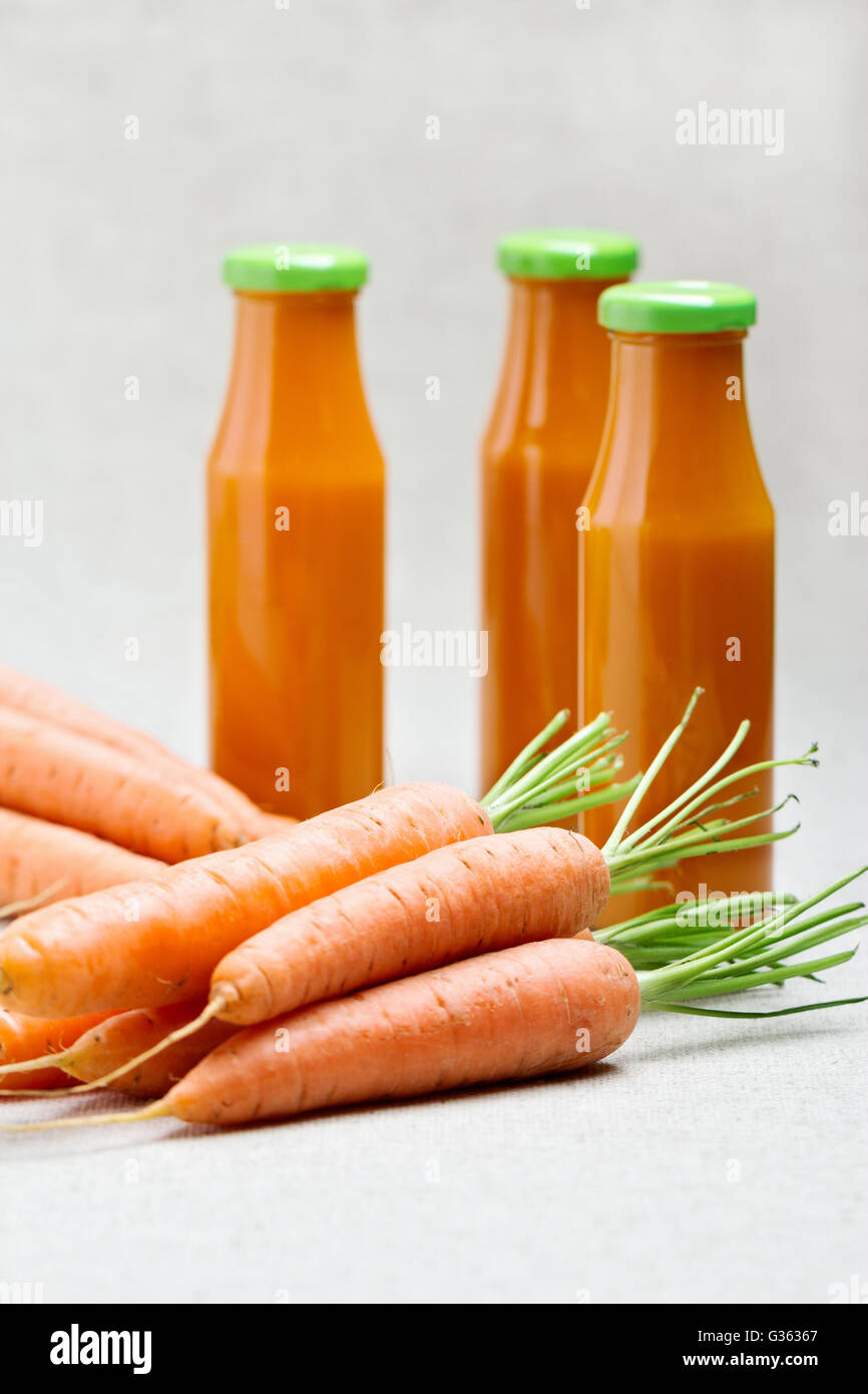 Trois bouteilles de jus de carotte avec des carottes. Focus sélectif. Banque D'Images