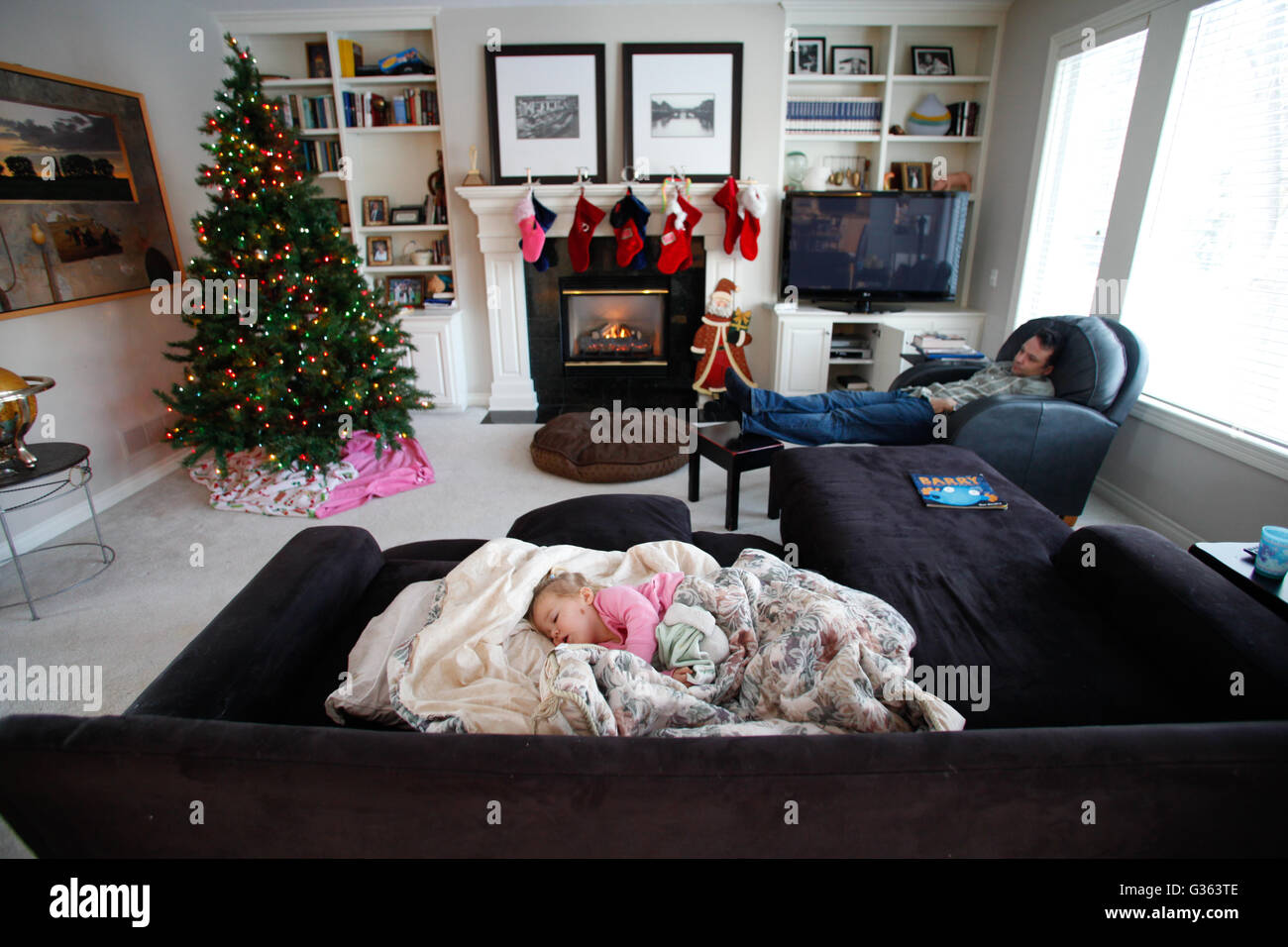 Un homme et un enfant dormir dans un salon, qui est décoré pour Noël, aux États-Unis, Banque D'Images