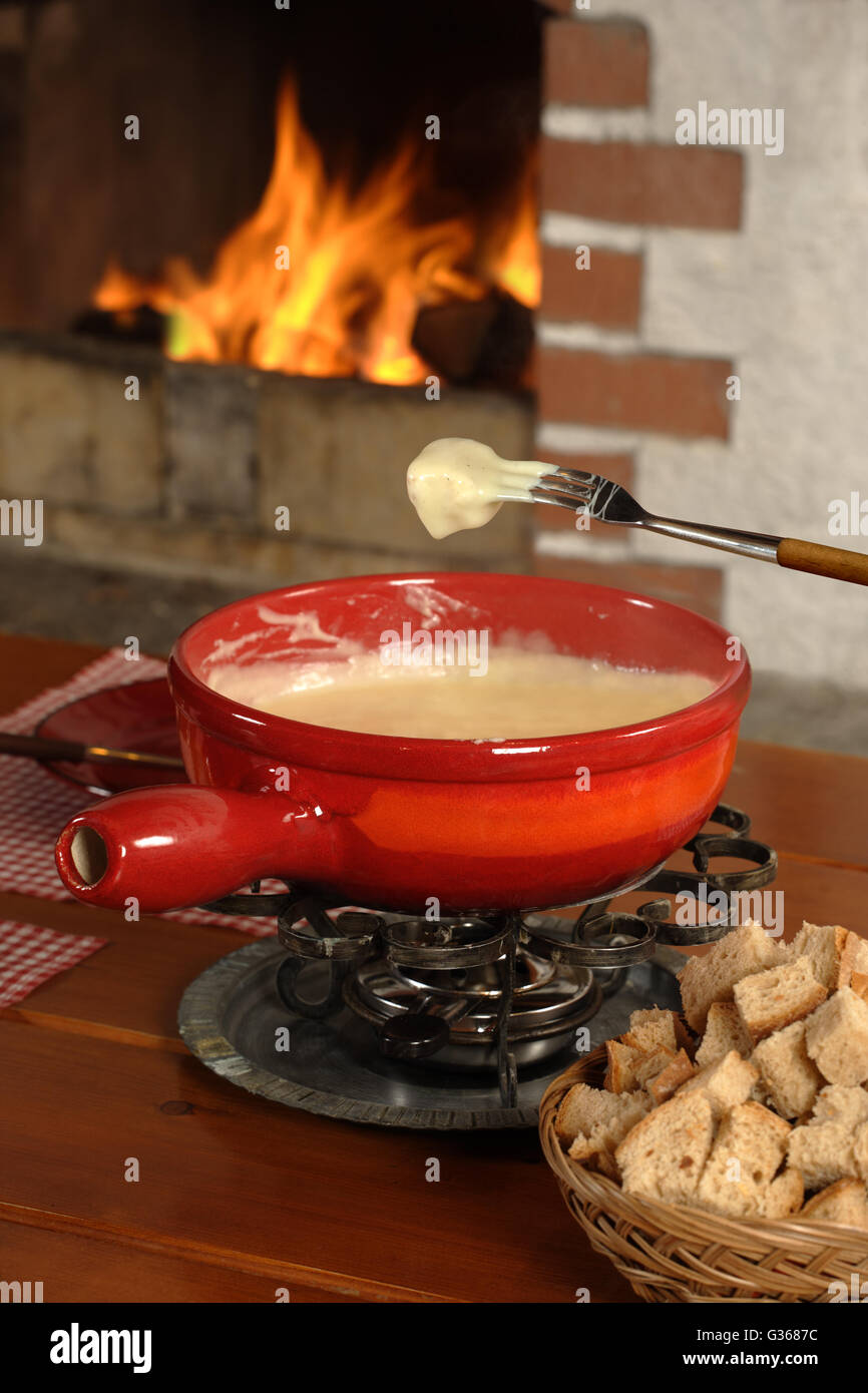Photo de pain trempé dans le fromage fondu dans le bol à fondue. Banque D'Images