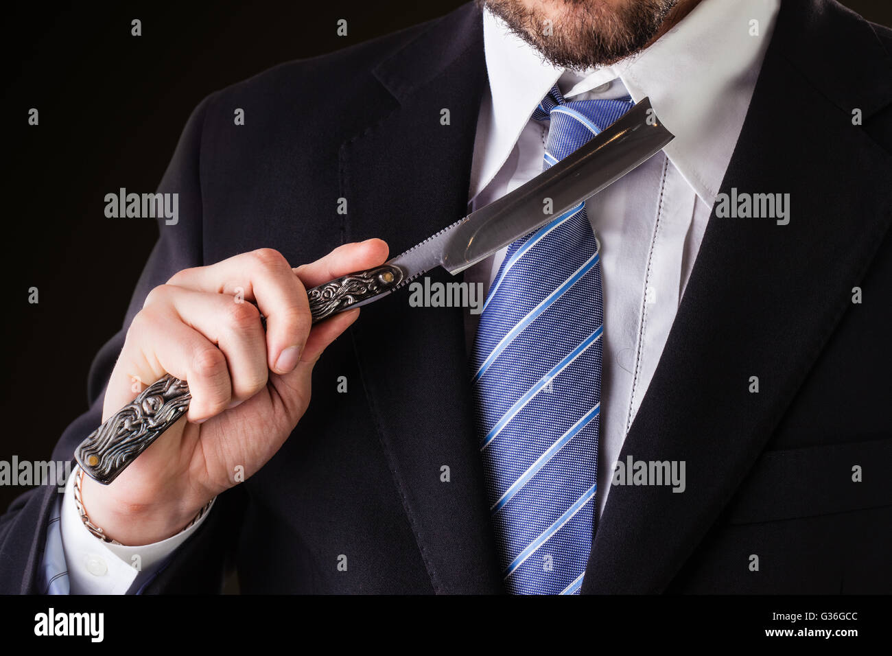 Un homme beau porter un costume et une cravate tenant un grand rasoir coupe-gorge Banque D'Images