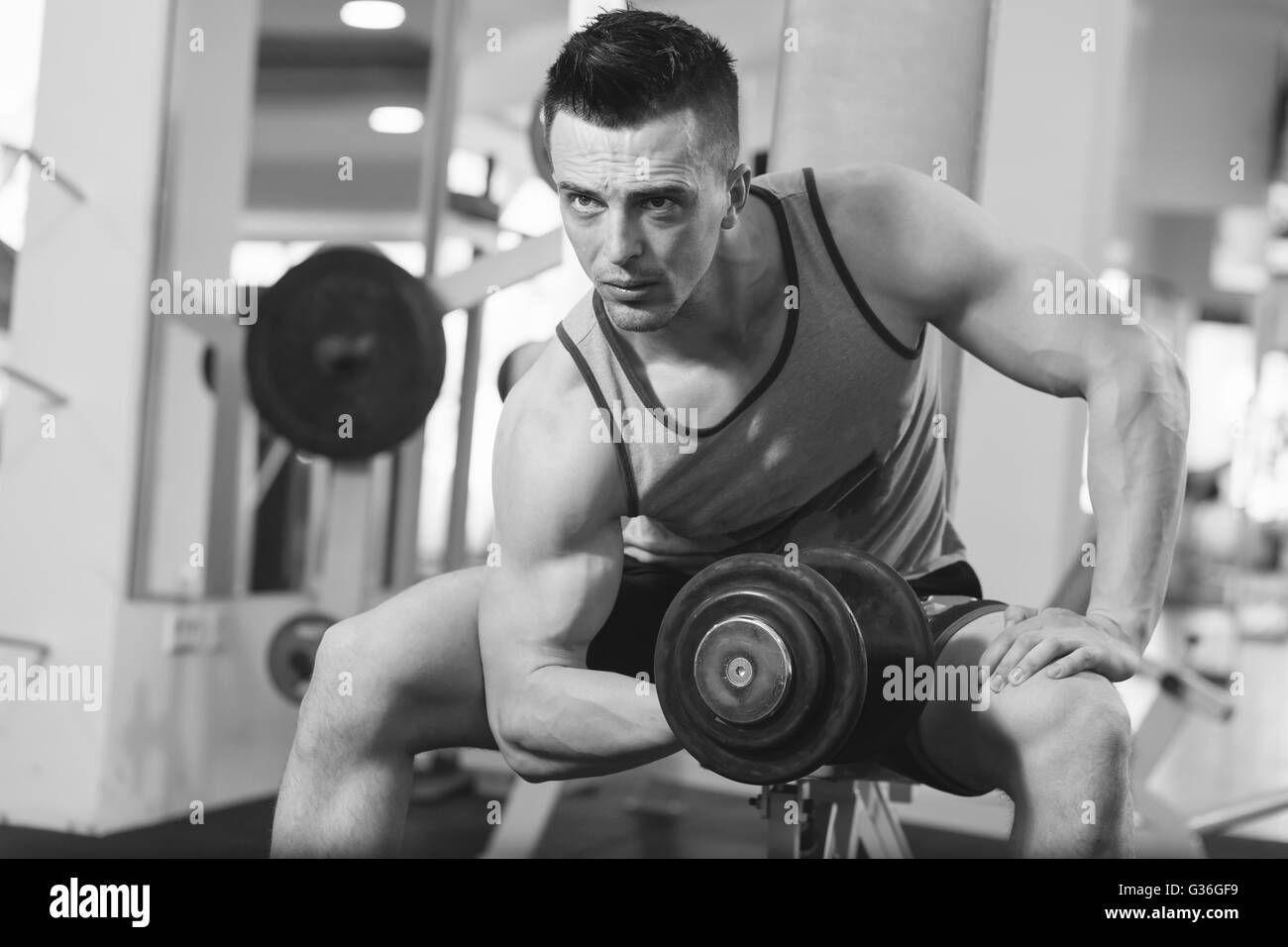 Jeune homme musclé faisant poids lourds pour l'exercice biceps avec  haltères en centre de remise en forme moderne Photo Stock - Alamy