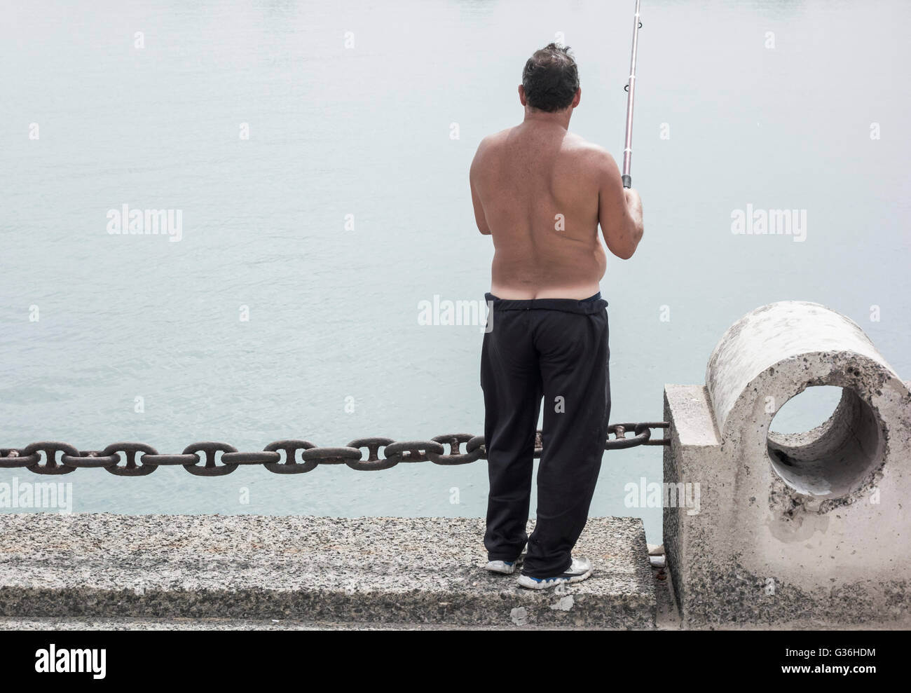 Man showing builders bum et marquée de pêche ligne tan docks en Espagne Banque D'Images