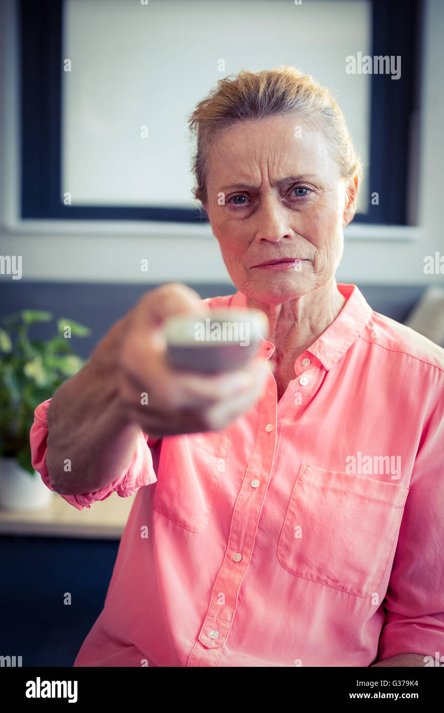 Senior woman changing tv channel Banque D'Images