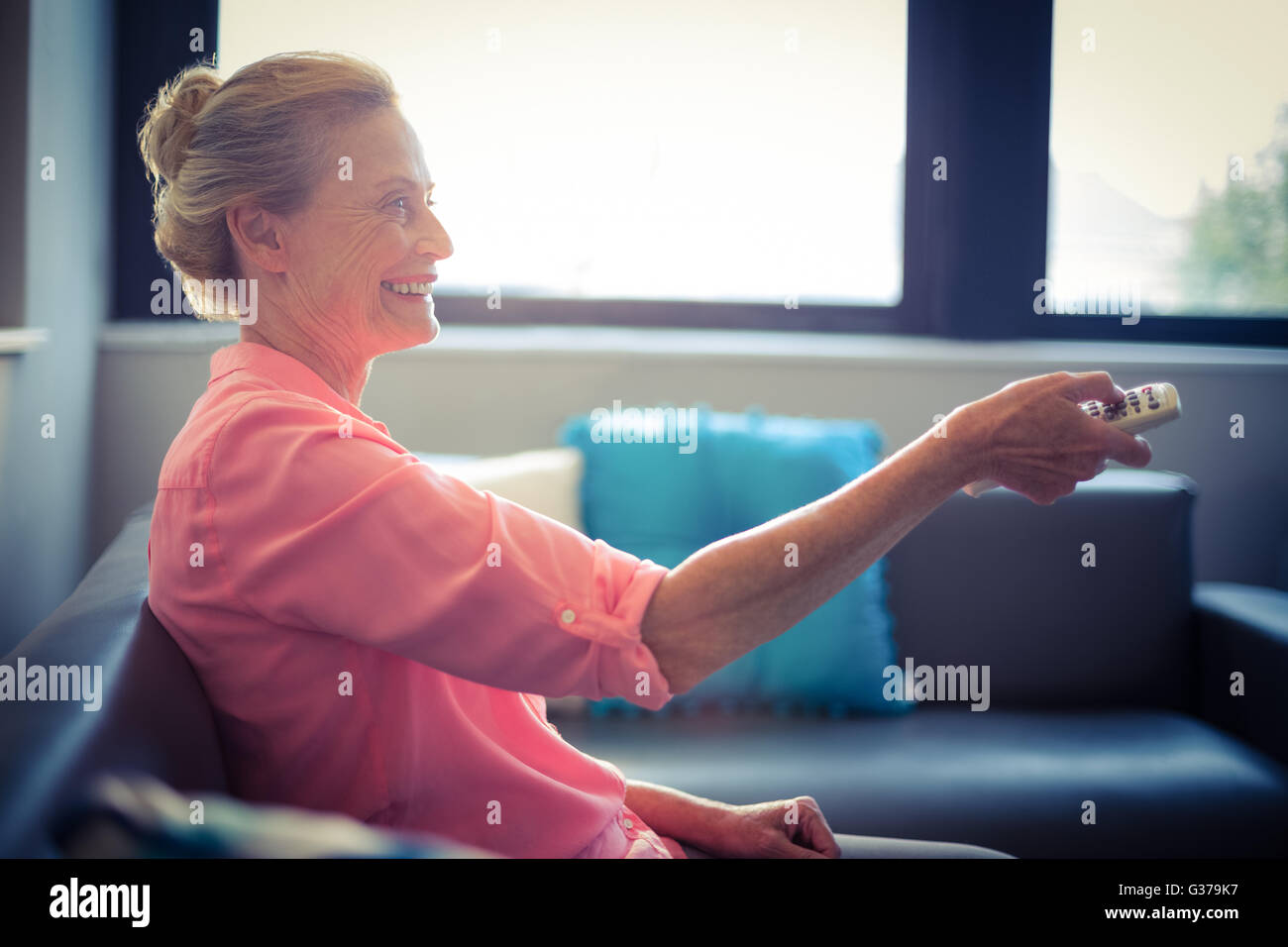 Senior woman changing tv channel Banque D'Images