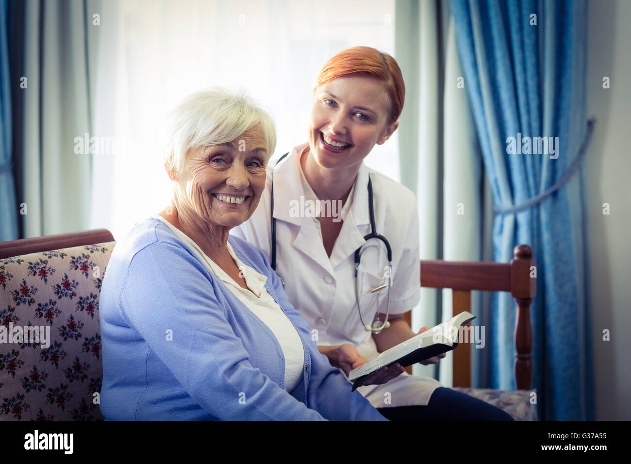 Smiling doctor helping senior woman pour lire un livre Banque D'Images