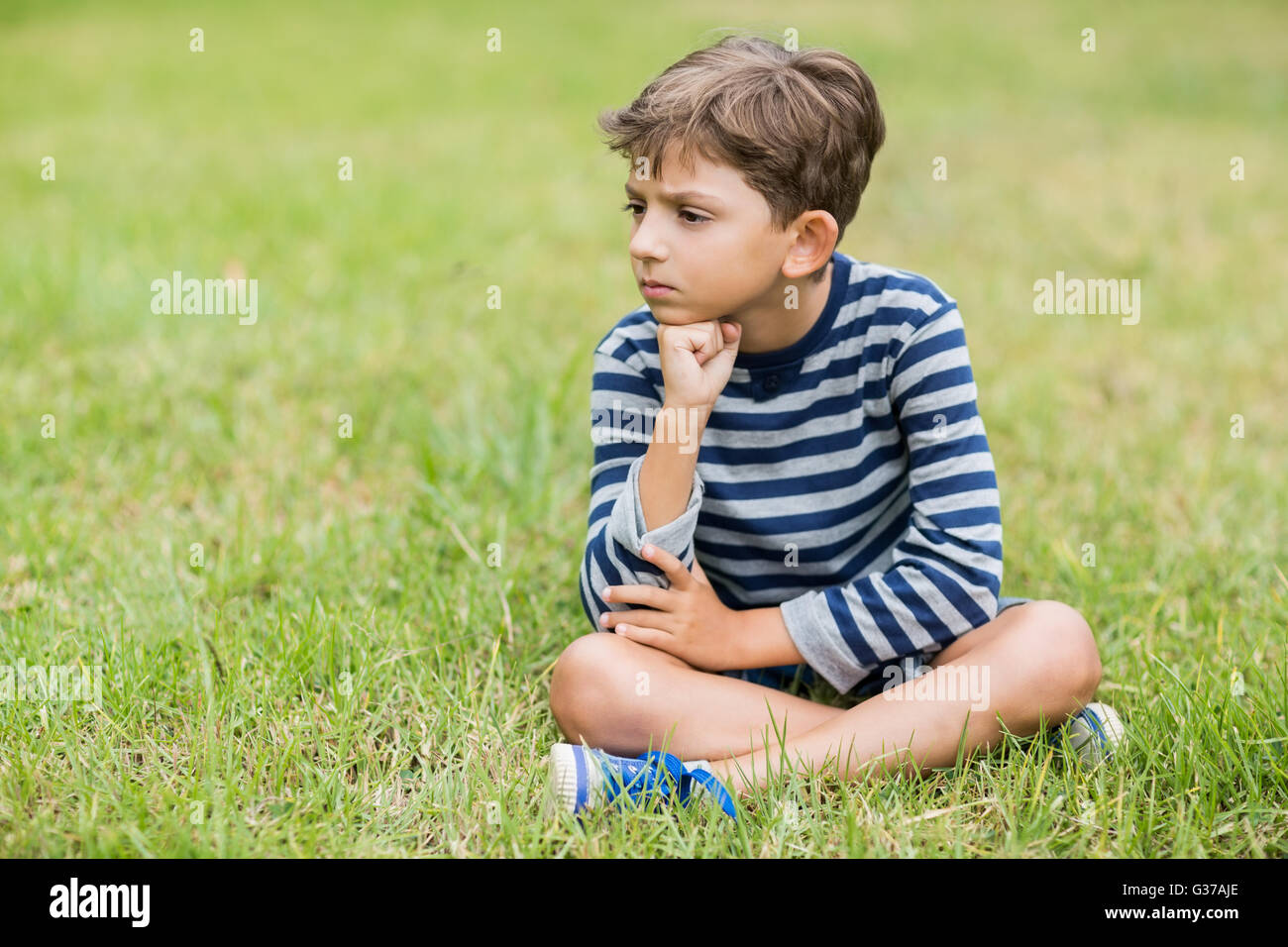 Fâché garçon assis sur l'herbe Banque D'Images