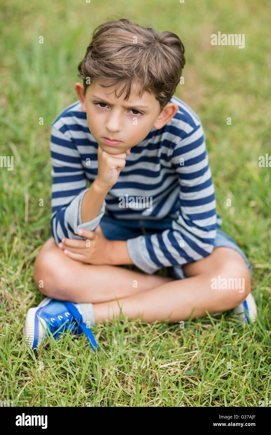 Fâché garçon assis sur l'herbe Banque D'Images