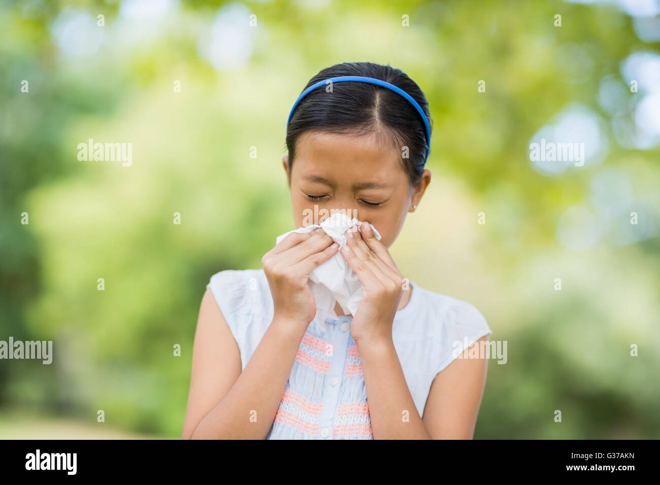 Girl blowing son nez avec un mouchoir lorsque l'éternuement Banque D'Images