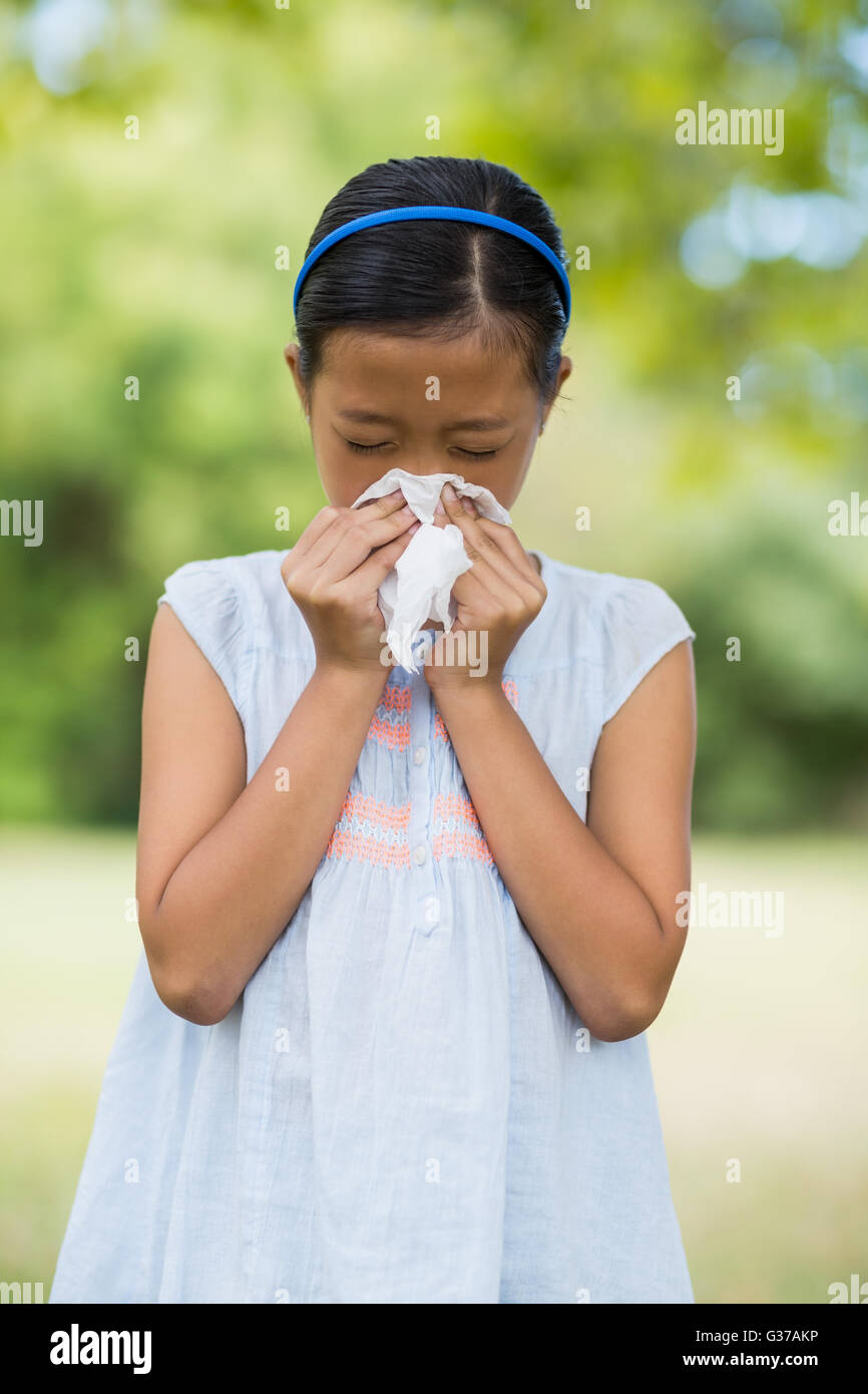 Girl blowing son nez avec un mouchoir lorsque l'éternuement Banque D'Images