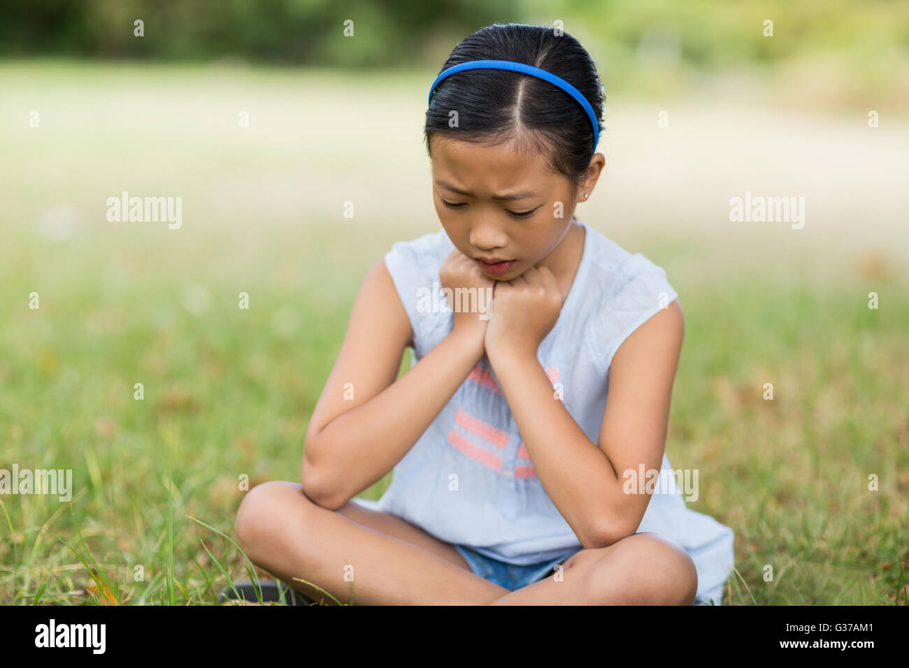 Upset girl sitting on grass Banque D'Images