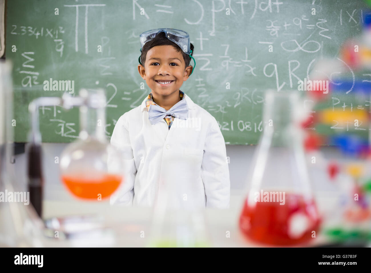 Smiling businesswoman standing in classe avec ballon chimique en premier plan Banque D'Images