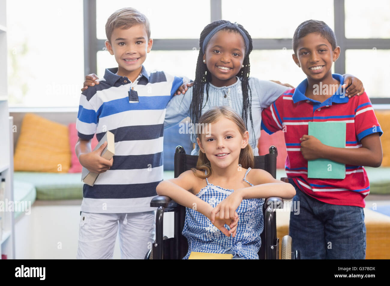 Les enfants de l'école souriant debout avec bras autour de in library Banque D'Images