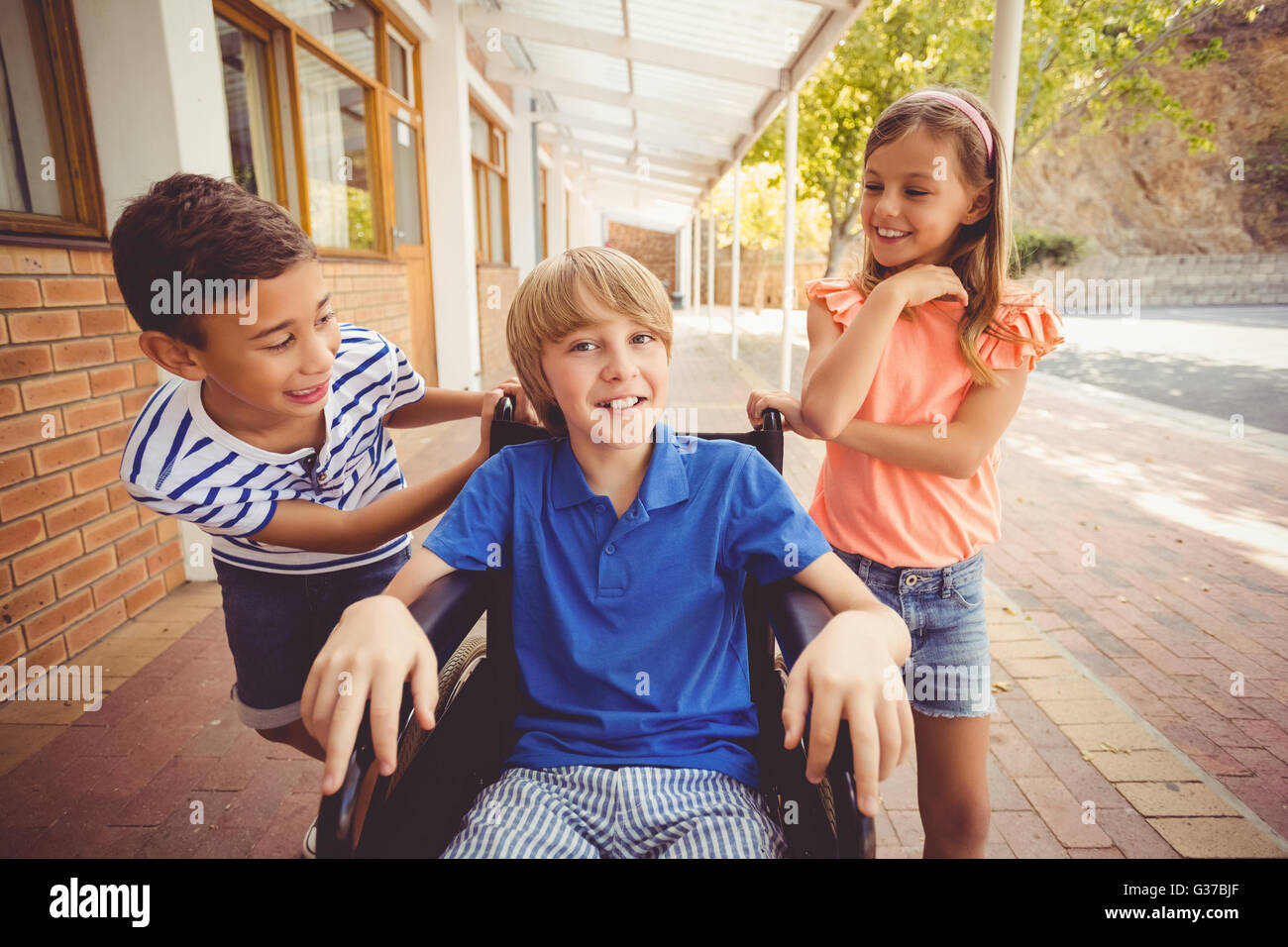 Les enfants de l'école de parler à un garçon en chaise roulante Banque D'Images