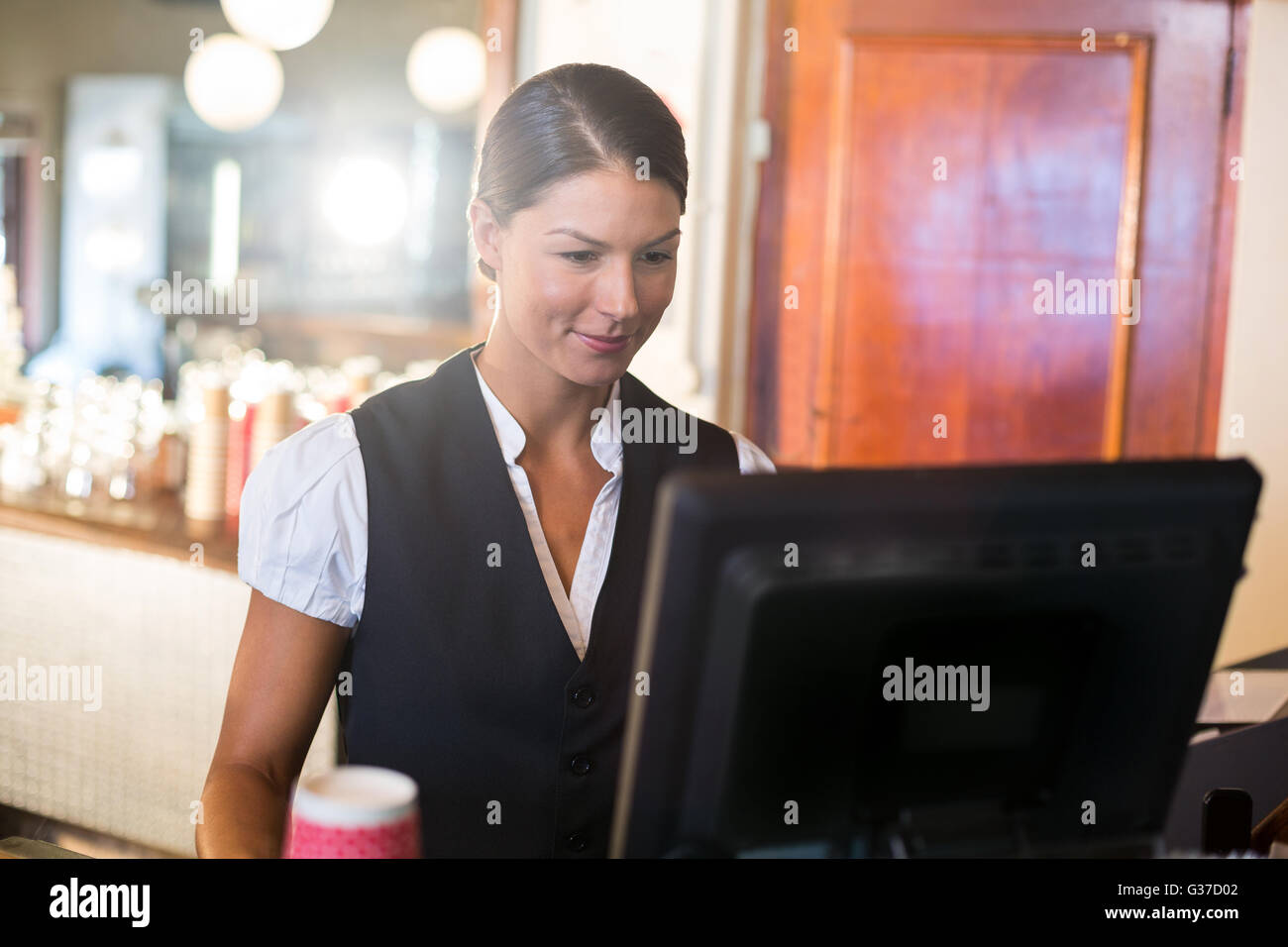 Waitress working on computer at counter Banque D'Images