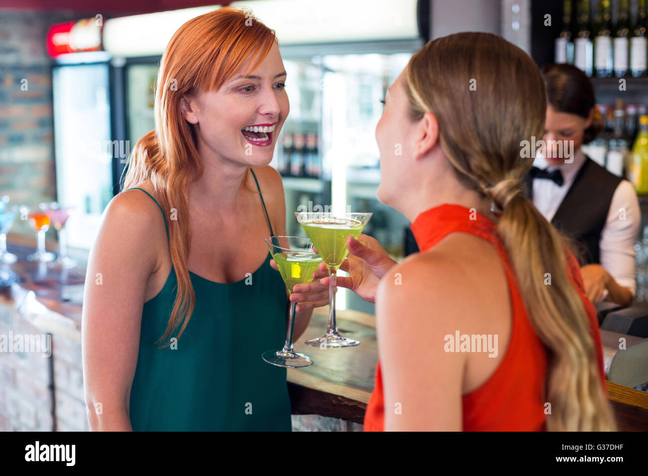 Happy friends holding a cocktail en face de comptoir bar Banque D'Images