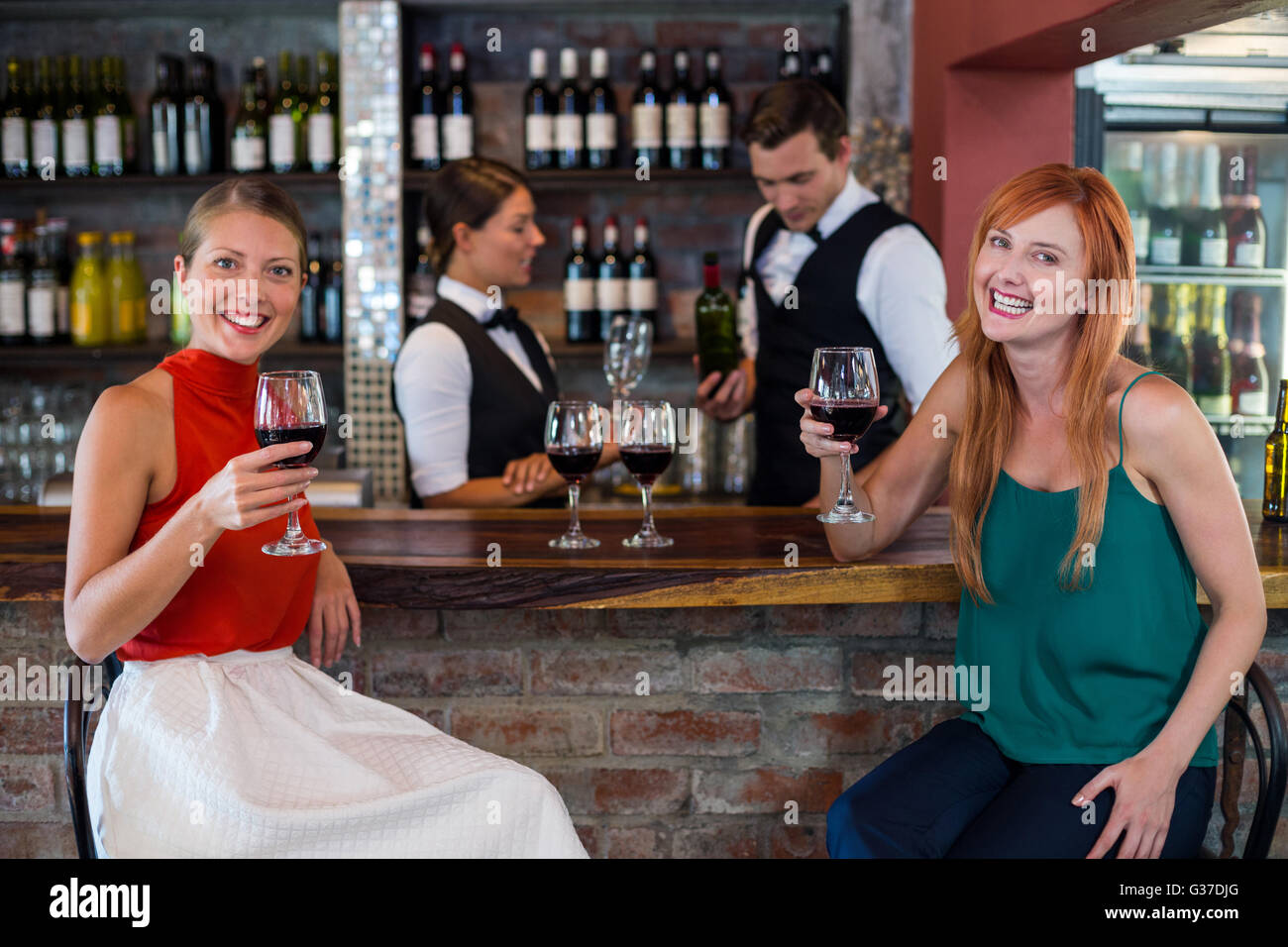 Portrait of happy woman holding un verre de vin rouge au comptoir du bar Banque D'Images