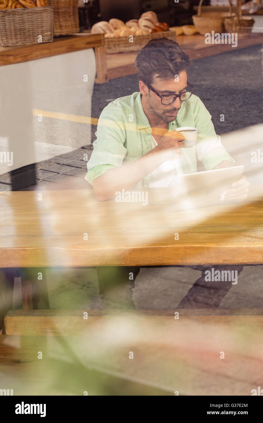 À l'aide d'un ordinateur tablette Hipster en buvant une tasse de café Banque D'Images
