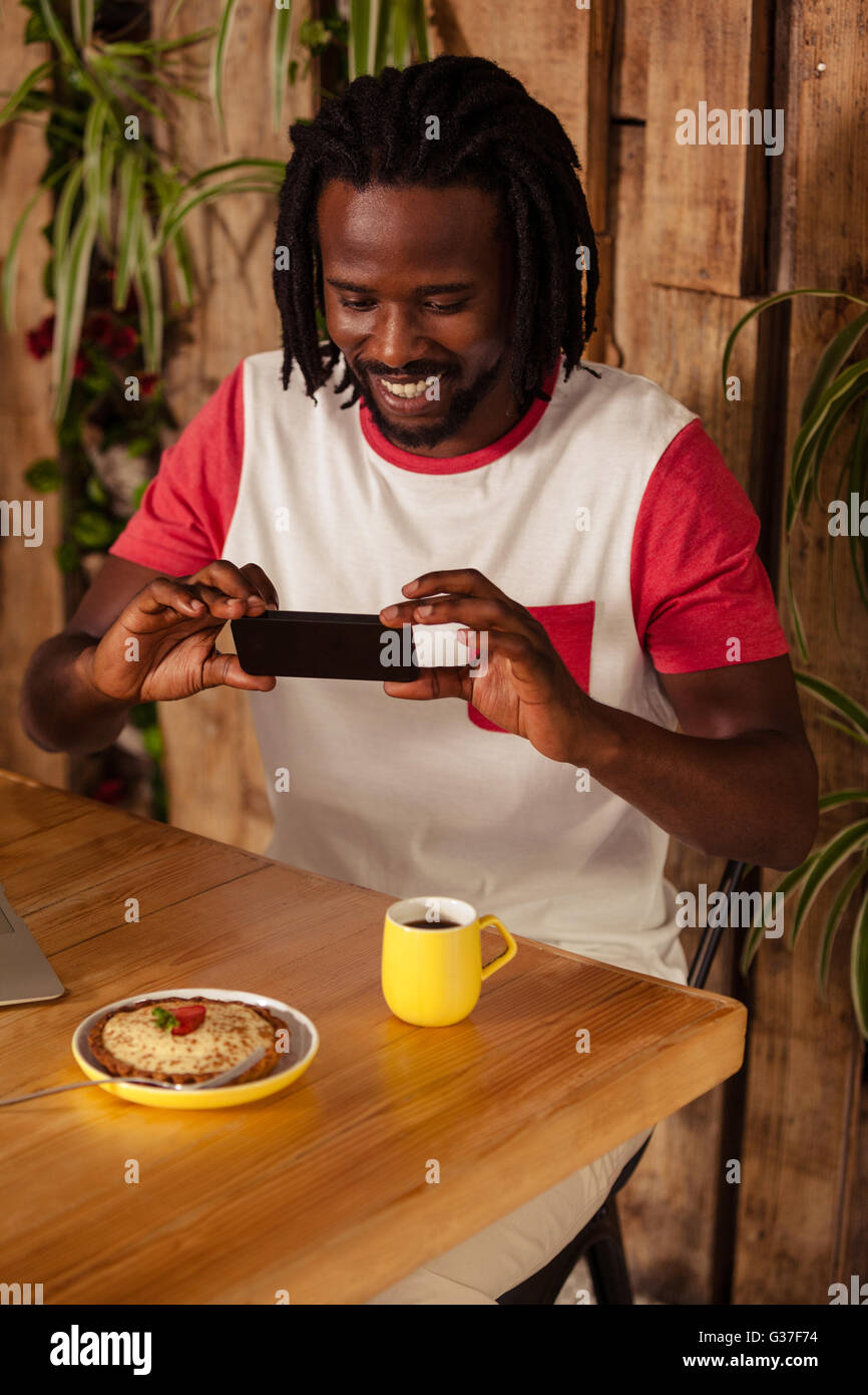 Casual man taking picture de pâtisserie et tasse de café Banque D'Images
