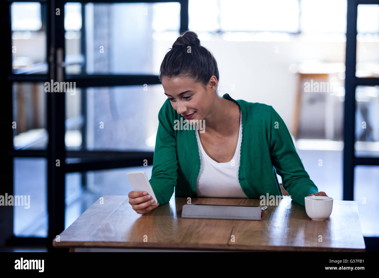 Businesswoman à son téléphone portable et la tenue d'un café Banque D'Images