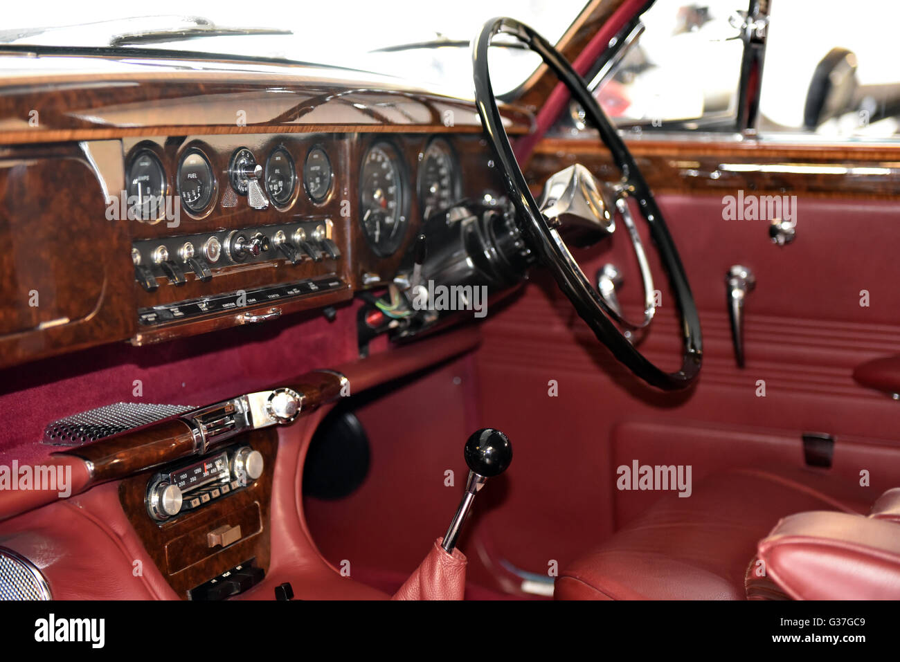 Tableau de bord de l'intérieur d'une Jaguar Type S classique, avec le noyer et cuir rouge, beaucoup de cadrans, de l'interrupteur et radio d'origine Banque D'Images