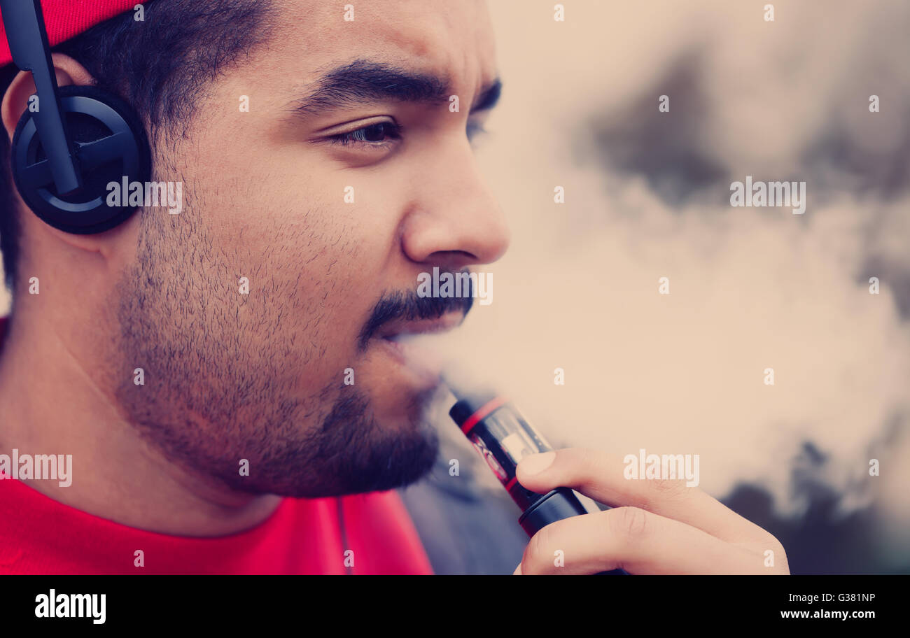 Portrait de garçon noir moderne à l'aide de e-cig vaporizer périphérique pour fumeurs de tabac liquide glycérine avec saveur. Gadget populaire chez les jeunes et qui veulent améliorer la santé et de cesser de fumer Banque D'Images