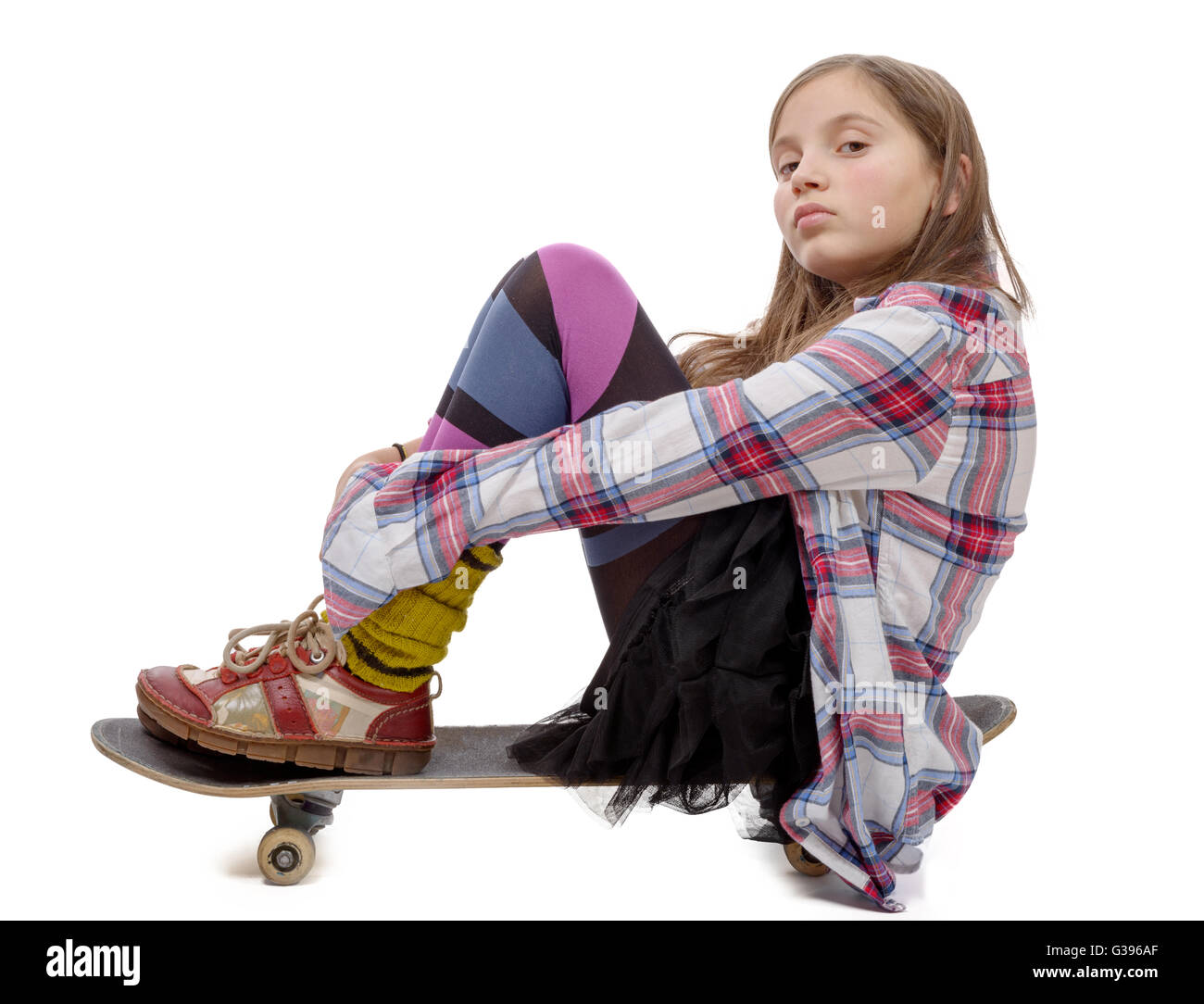 Pretty young girl posing with a skateboard, assis sur le skate, sur blanc Banque D'Images
