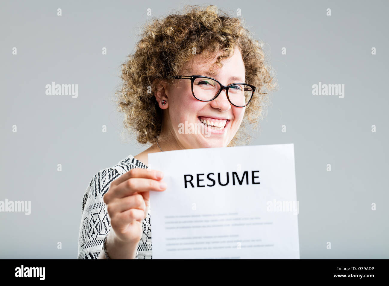 Femme bouclés sur un fond neutre montrant son curriculum vitae Banque D'Images