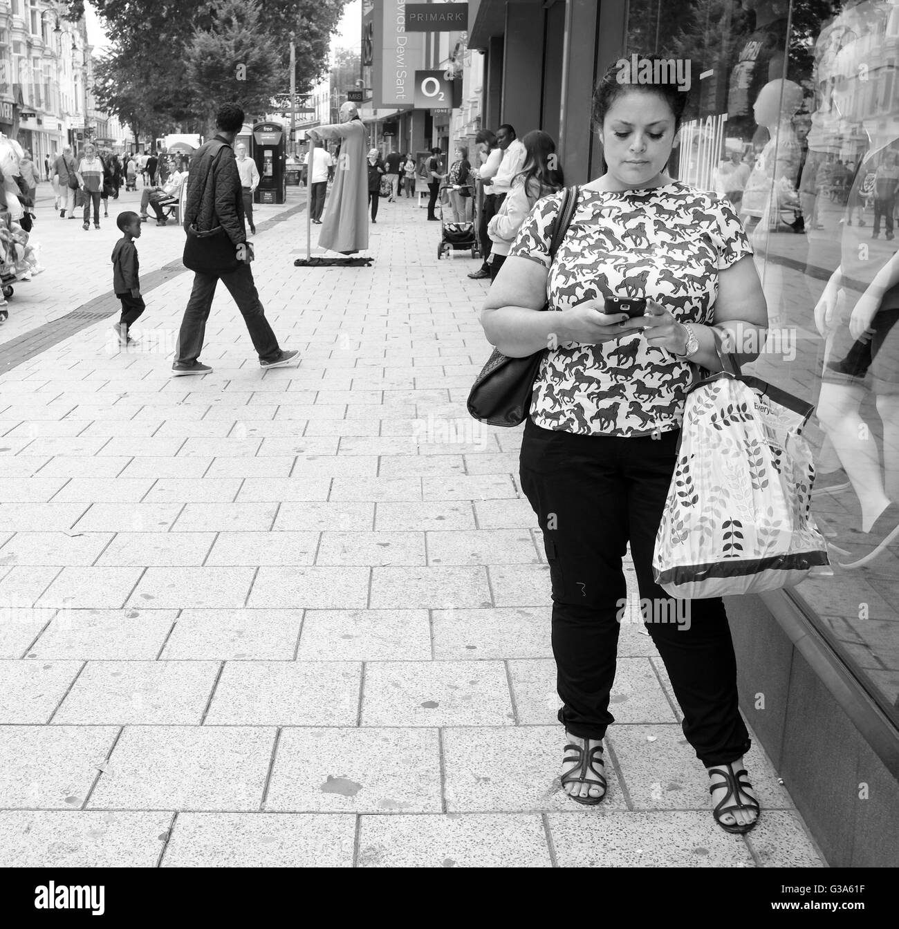 Juin 2016 - Jeune femme avec son téléphone mobile dans le centre de Cardiff. Banque D'Images