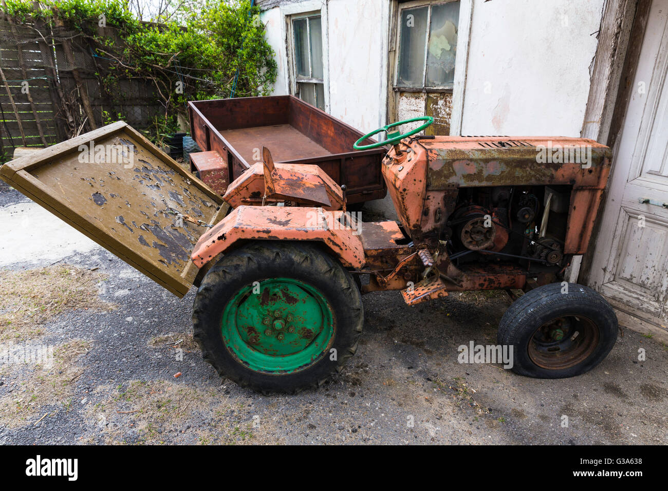 Old vintage rouille du tracteur à l'écart à l'extérieur, près de la maison de village Banque D'Images