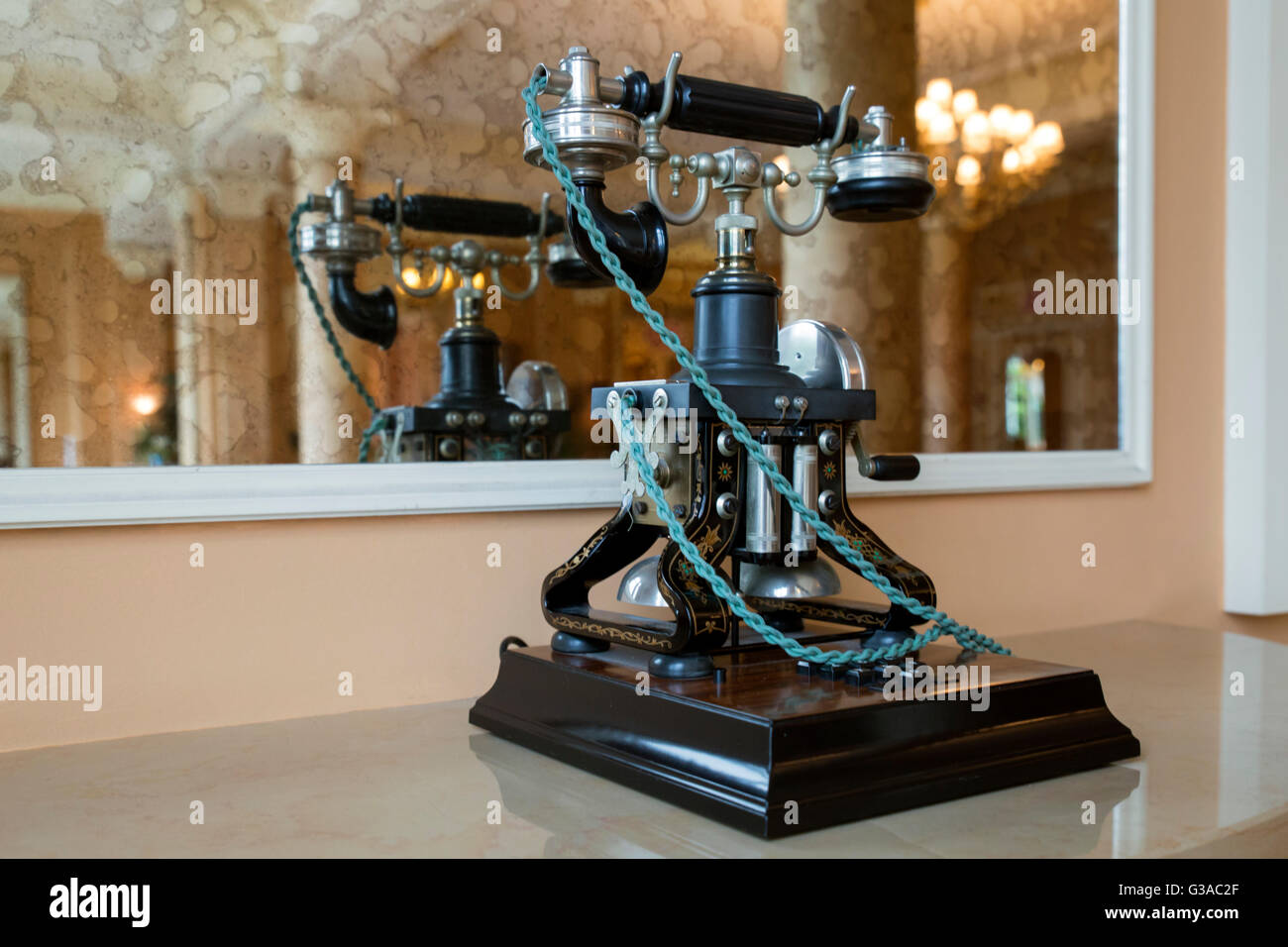 Un vieux téléphone noir avec cordon vert en face d'un grand miroir. Banque D'Images