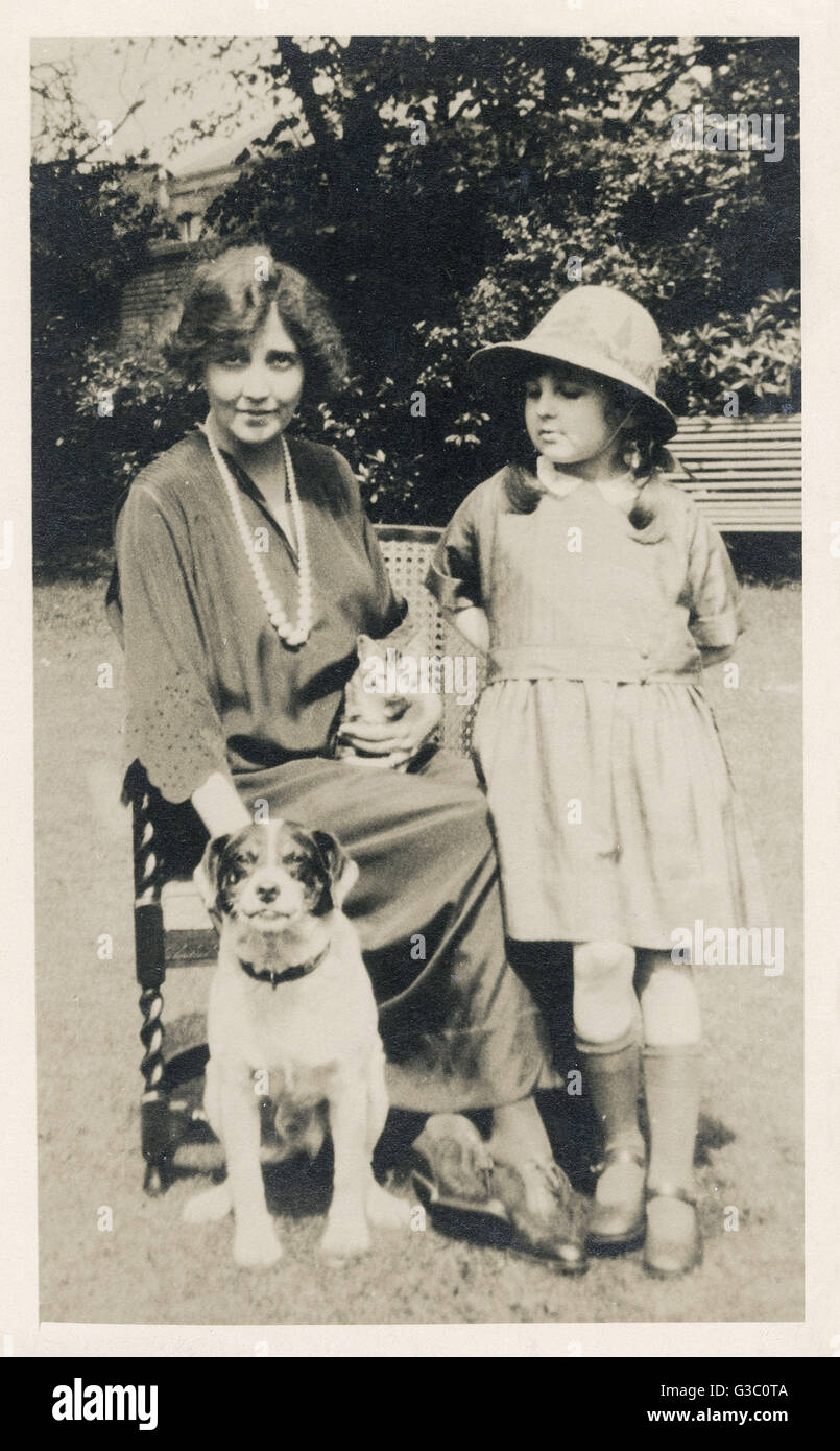 Femme et fille avec chien et chat dans un jardin Banque D'Images