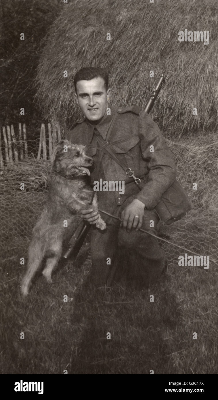 Homme en uniforme avec un chien terrier dans une ferme Banque D'Images