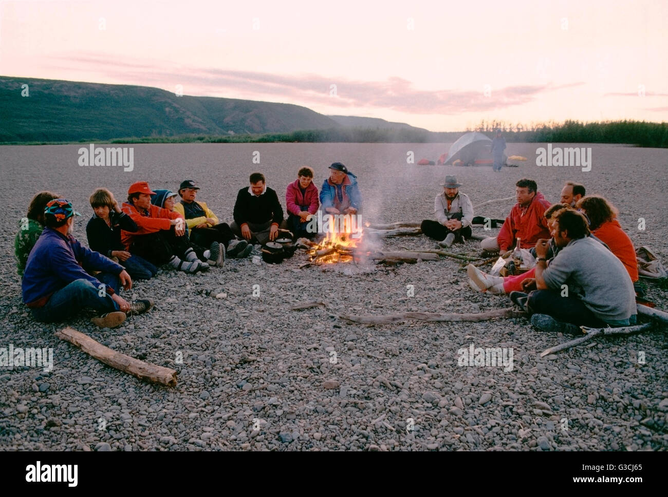 Les voyageurs d'aventure américaine avec guides soviétique s'asseoir autour d'un feu de camp, Belaya River, Magadon Région, Sibérie, frmr Union Soviétique Banque D'Images