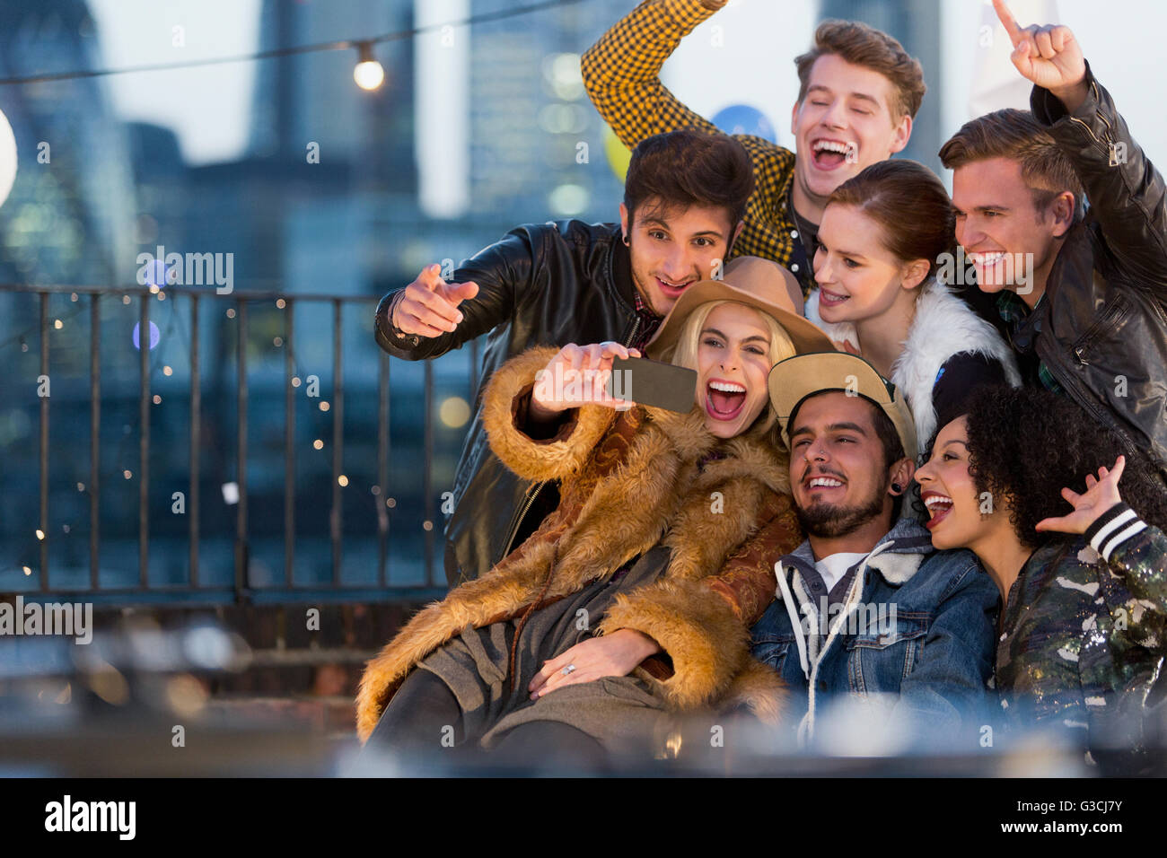 Jeunes adultes enthousiastes friends at rooftop party selfies Banque D'Images