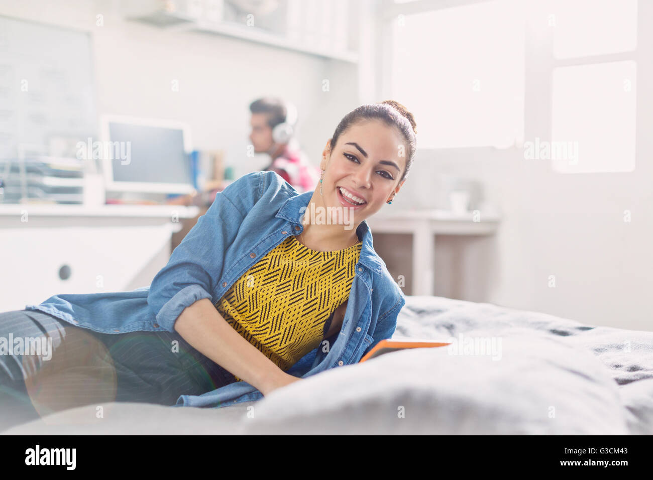Portrait of smiling young adult woman reading on bed Banque D'Images