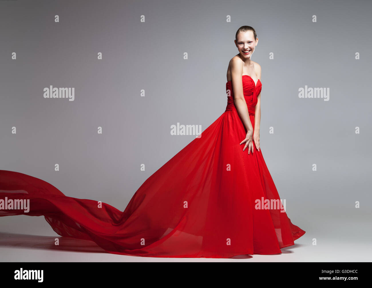 Belle jeune fille en robe rouge avec jupe volants looking at camera Banque D'Images