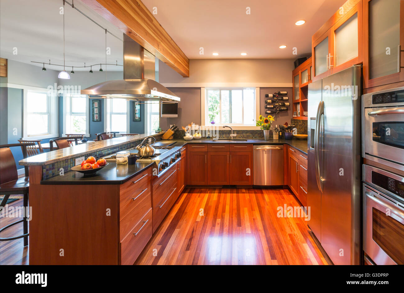 Spacieuses, contemporaines accueil gamme cuisine intérieur avec des armoires en bois et planchers, éclairage d'Accent et d'accessoires en acier inoxydable Banque D'Images