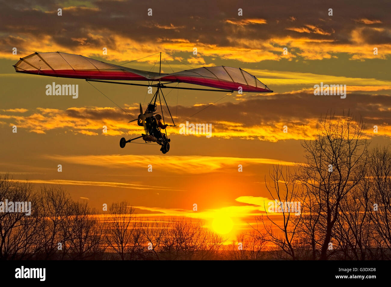 Le deltaplane motorisé voler dans le coucher du soleil Banque D'Images