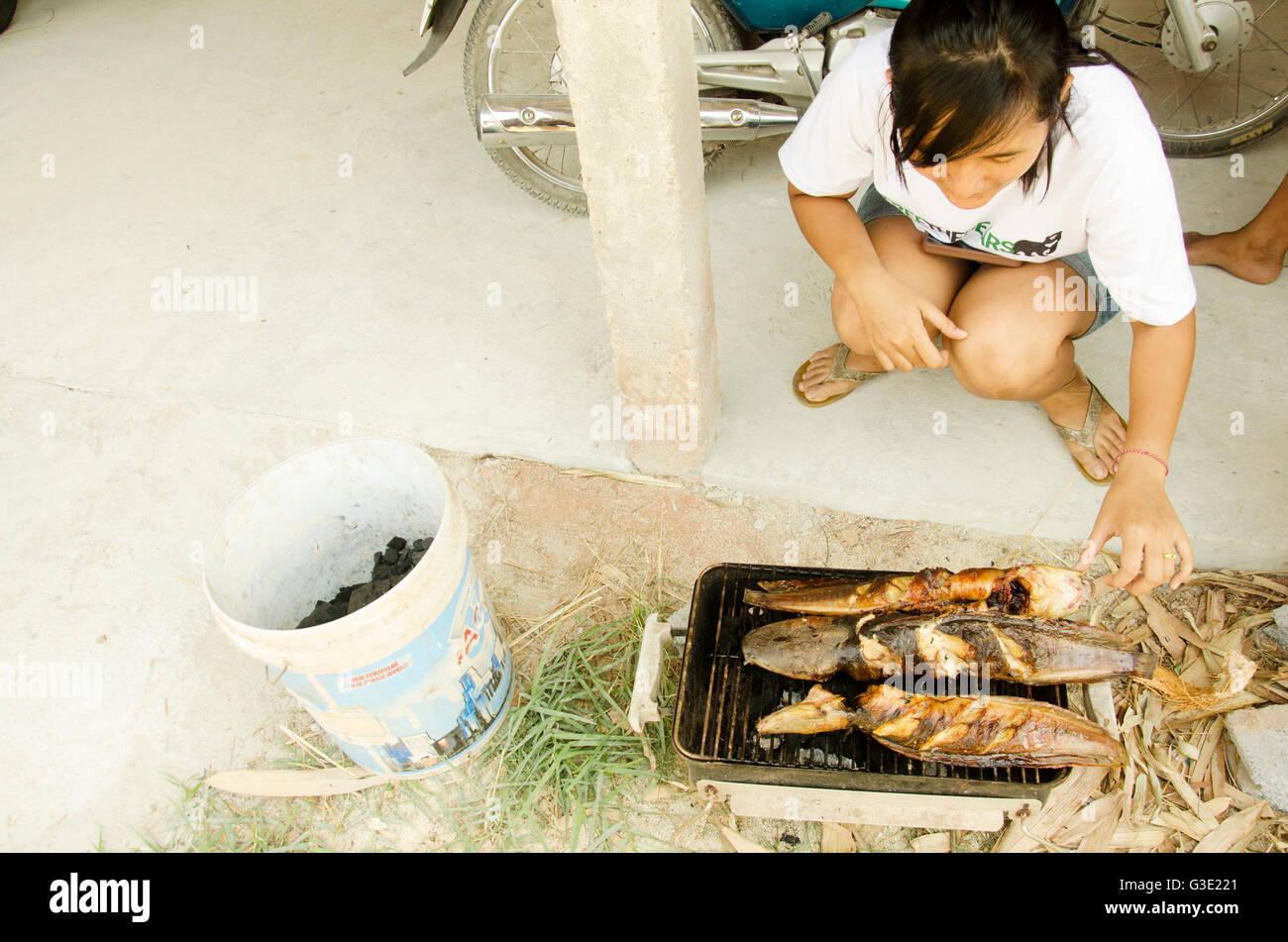 Les femmes thai cooking clarias est une espèce de poisson-chat marche thai style frites grillées sur vieille cuisinière Banque D'Images