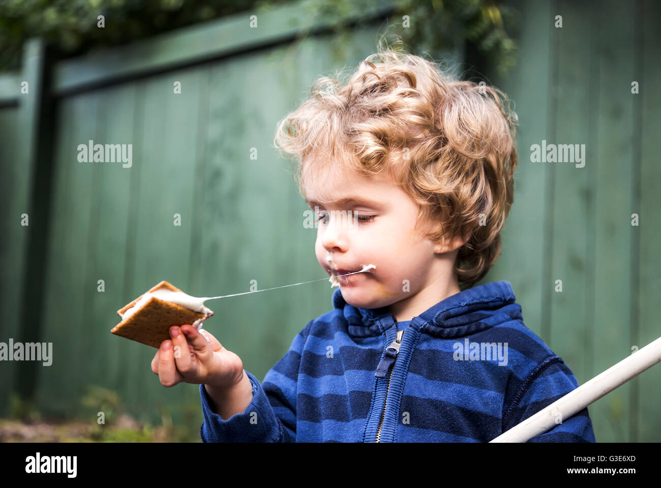 Jeune garçon mangeant une s'more à l'extérieur et se collant ; St. Albert, Alberta, Canada Banque D'Images