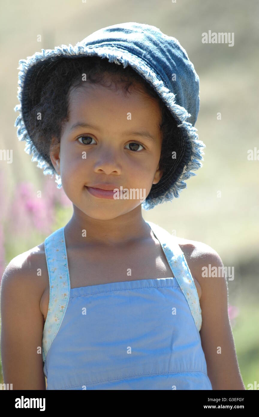 Mixed Race jeune fille avec chapeau bleu denim et pinafore dress Banque D'Images